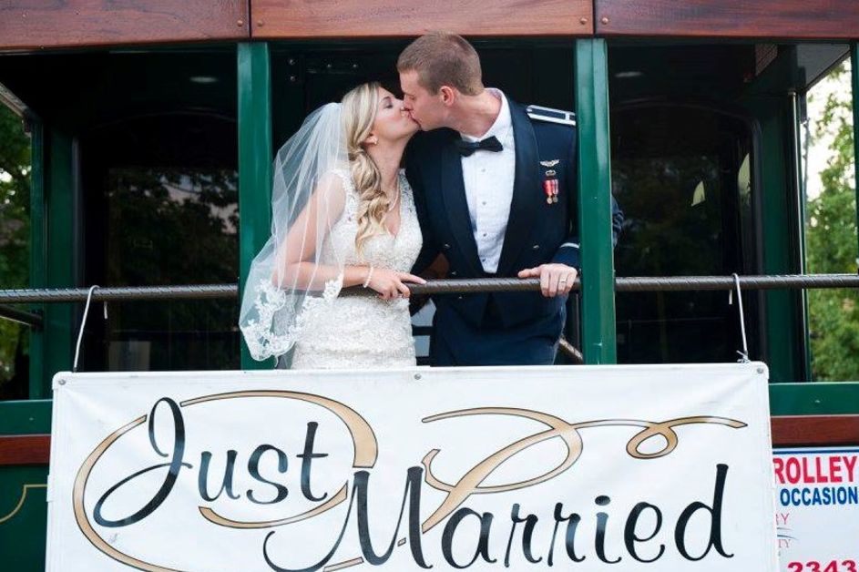 Bride and groom kissing on back of trolley behind "Just Married" sign