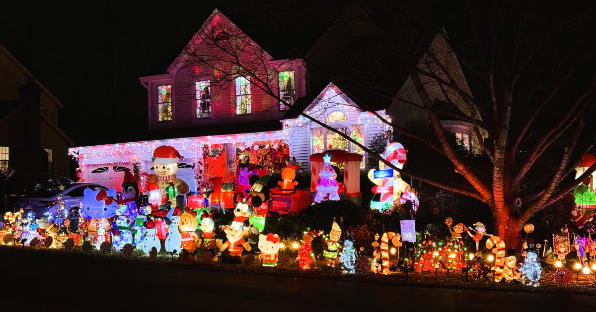 a residential home decorated with christmas lights and the front and side yards completely filled with inflatable decorations of christmas themed characters