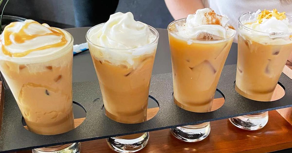 Four small drinking glasses filled with coffee and topped with whipped cream