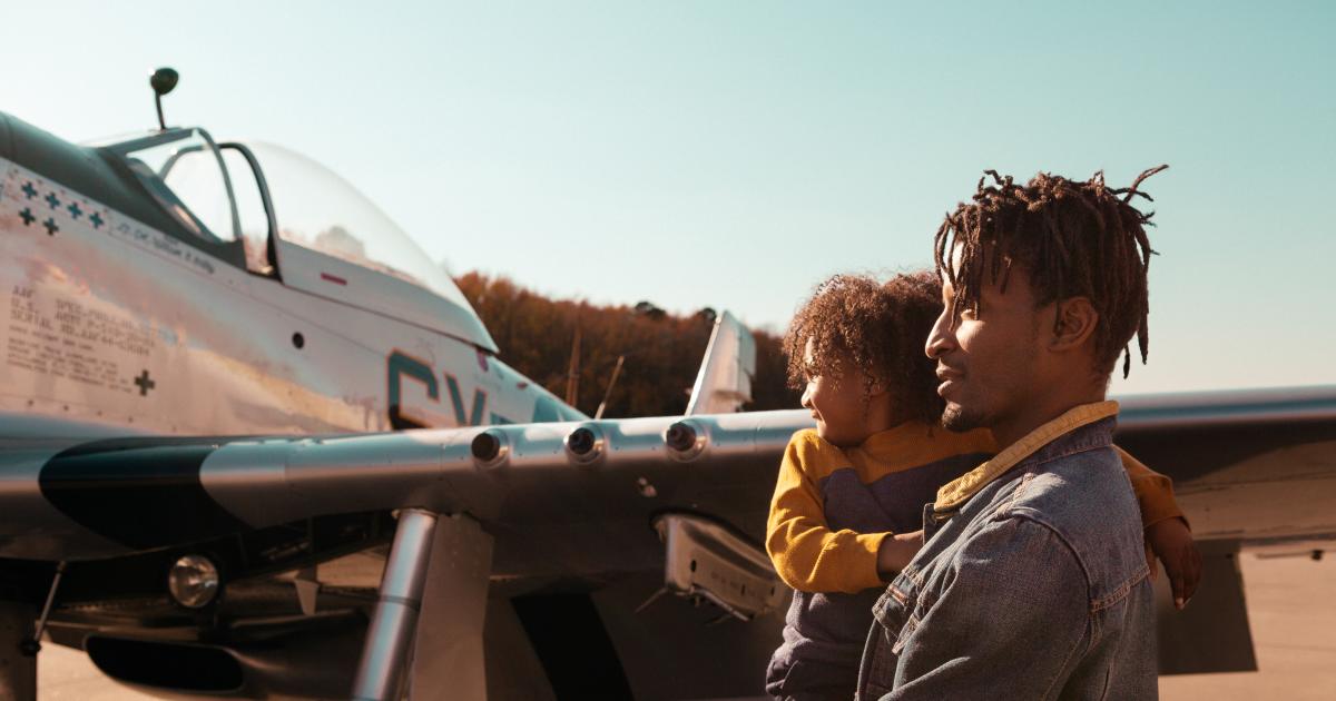 man holding a boy looking at an airplane outside at a museum
