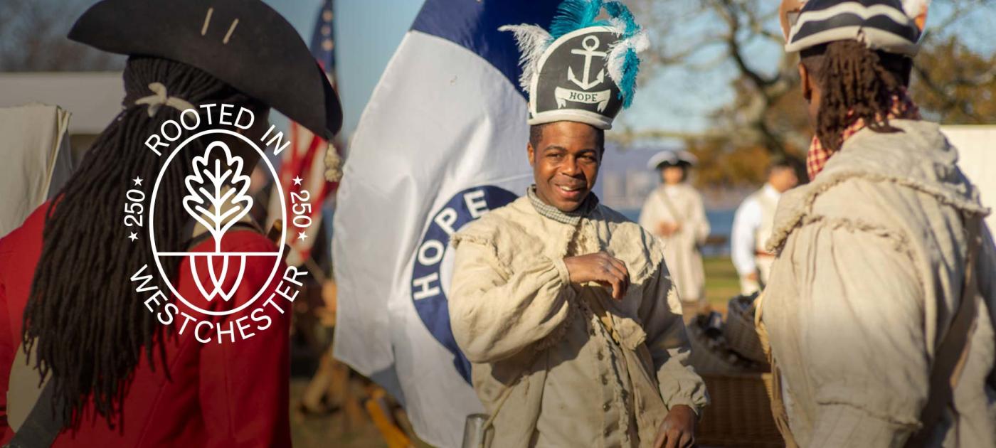 Rhode Island regiment members with flag (Steve Thomas facing camera wearing headgear with Hope and blue feathers
