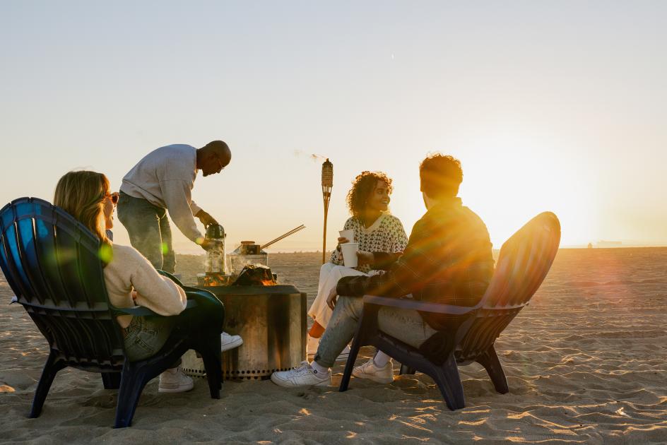 Group of people sitting around a bonfire, perfect for Meetings and beachside things to do in Huntington Beach