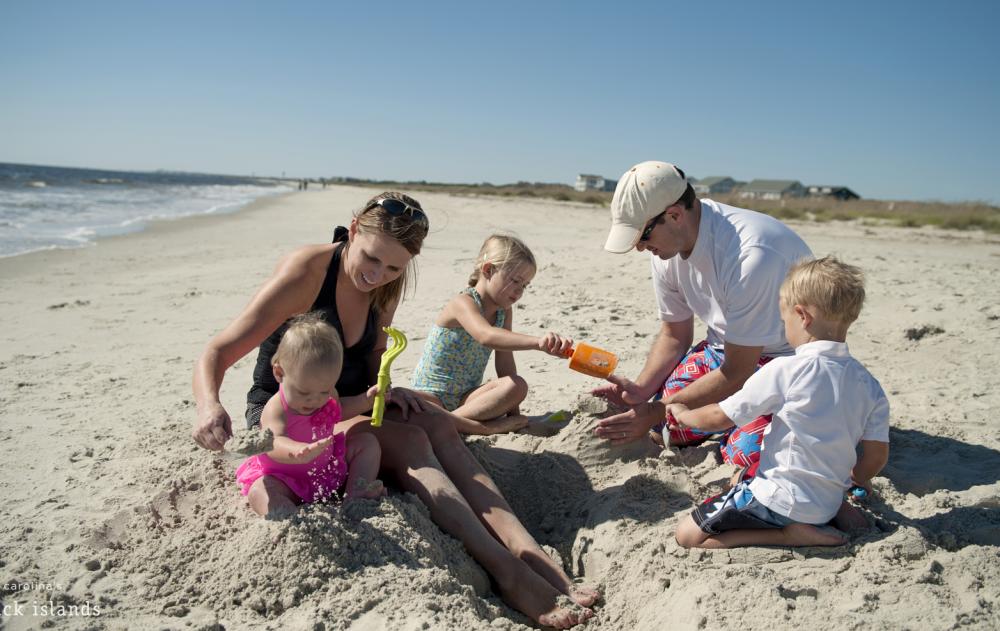 Family building sandcastles on Caswell Beach, NC.