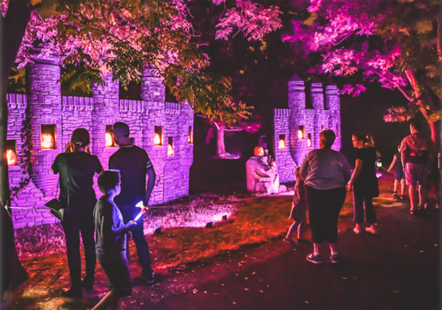 Families at Lincoln Hill Farms at night, looking at jack-o'-lanterns on a castle wall