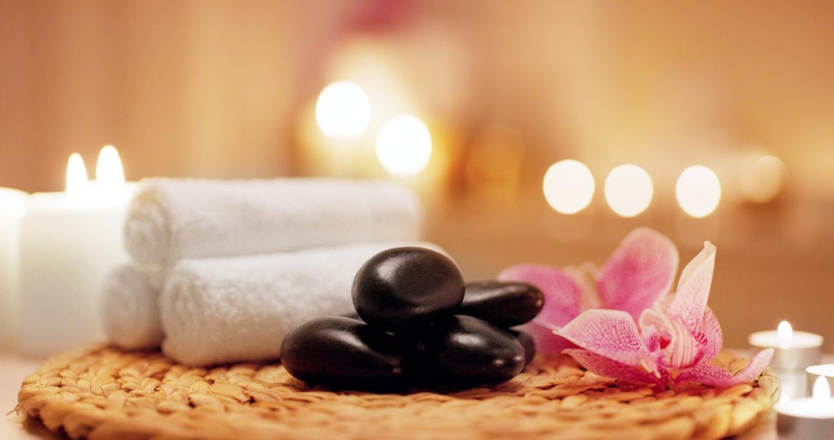 spa set up - table with stones, flowers, towels and lit candles