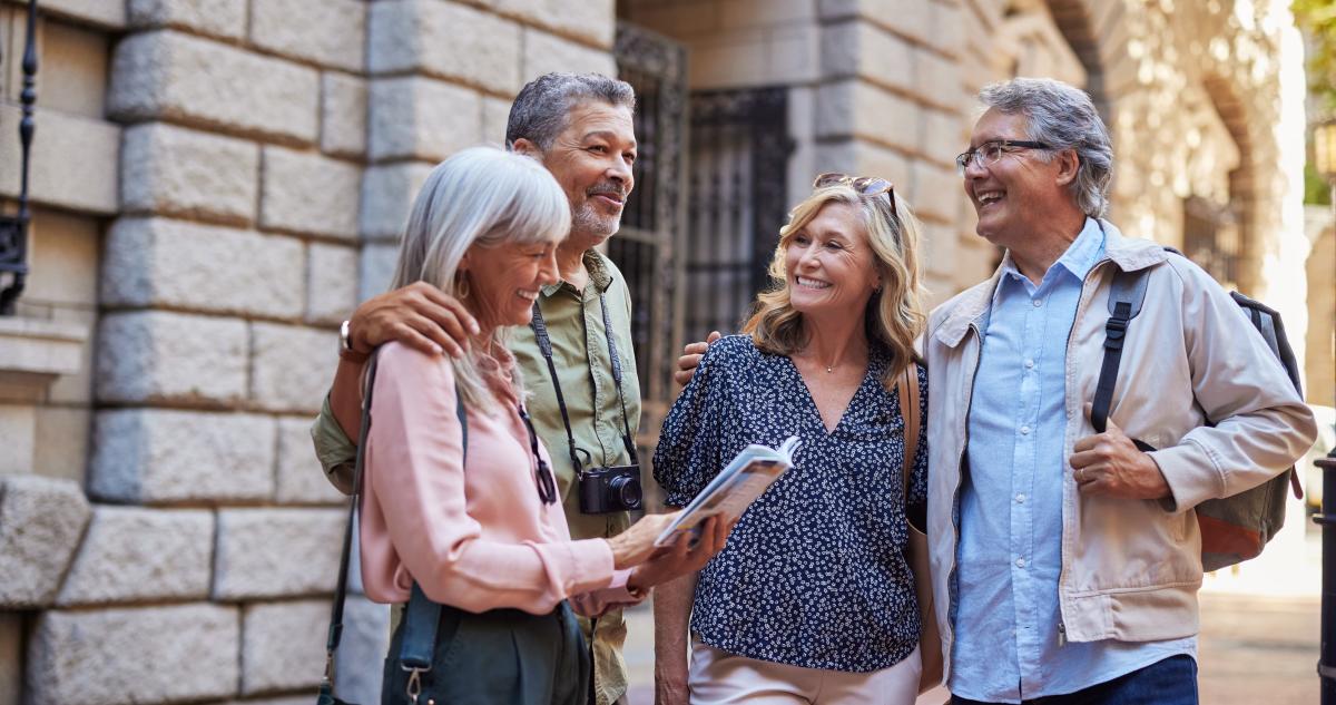 A group of older people look at a brochure as they tour a destination.