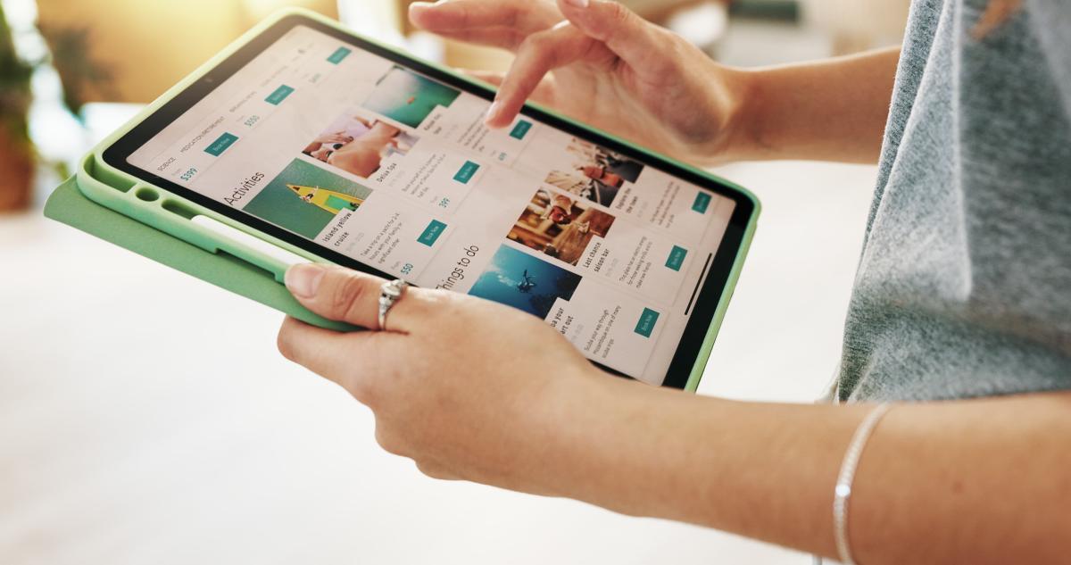 Person using a tablet to browse activity options on a travel booking website.