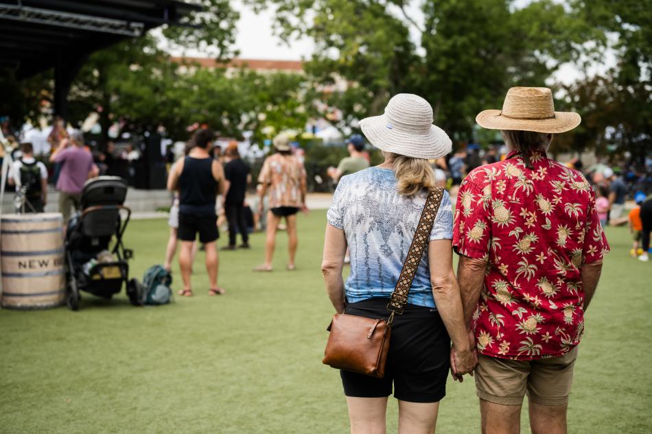 A couple holding hands while they listen to music on the New Belgium stage.