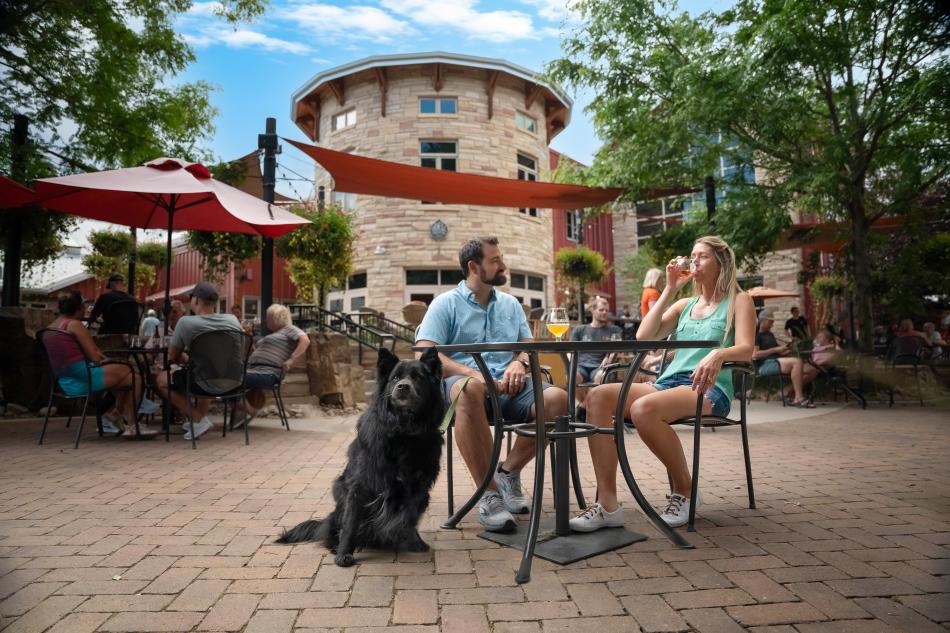 A couple with dog drinks beer at Odell Brewing Company patio