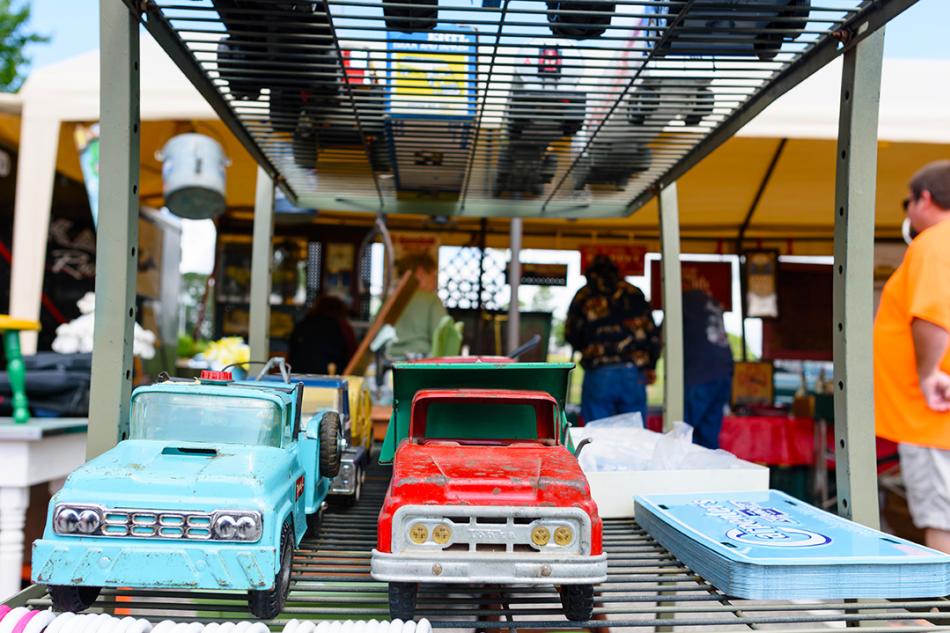 Toy trucks lined up for sale on a shelf at a yard sale