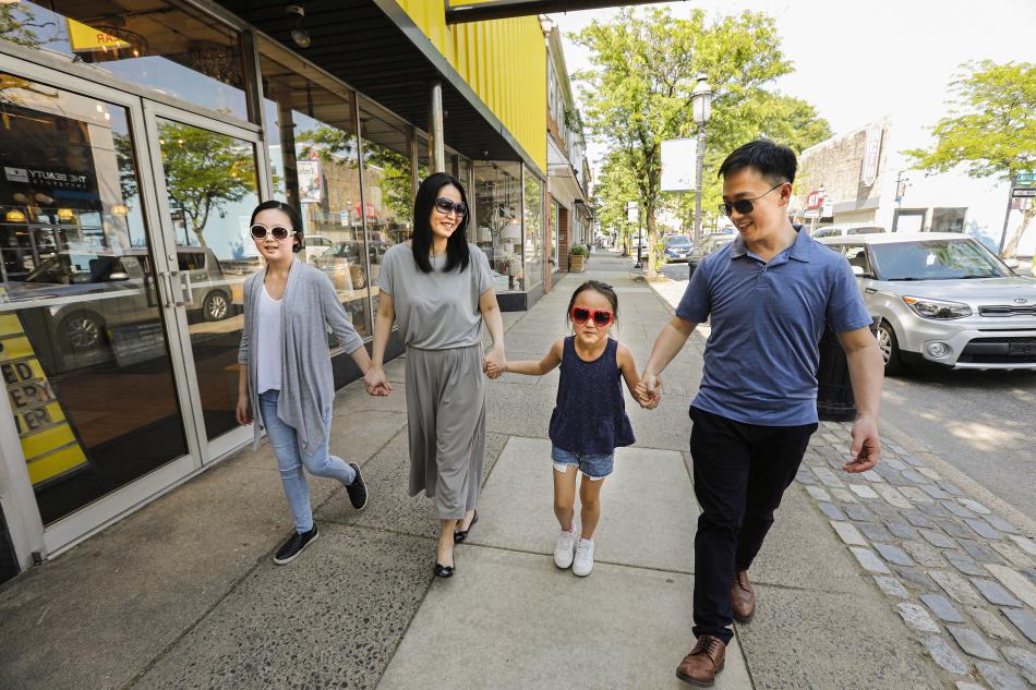 A family  of four holds hands while walking down Main Street in Ambler