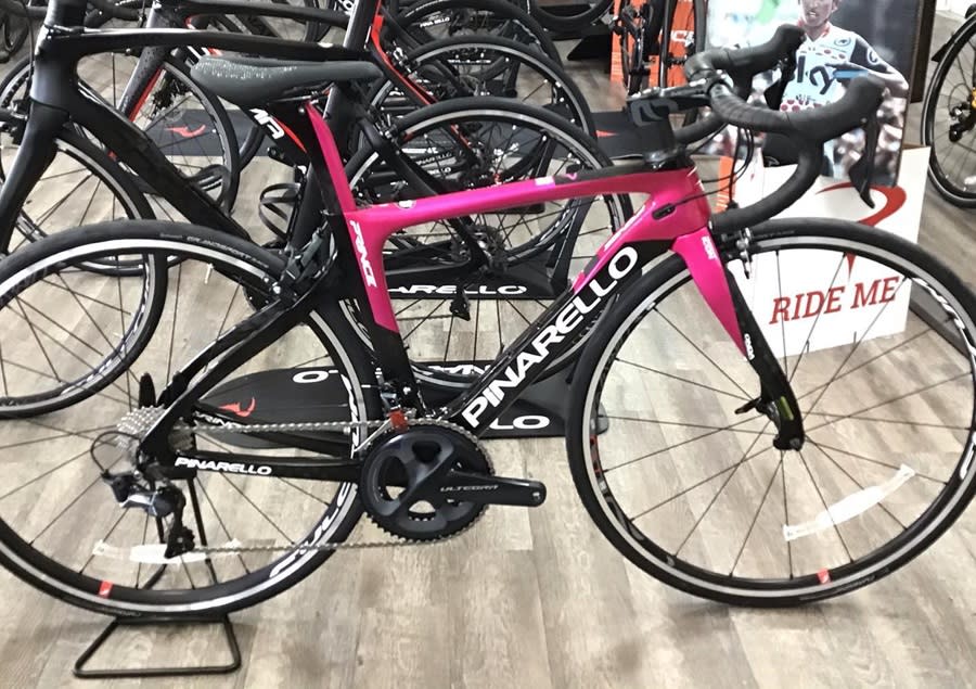 A pink road bike on display in a bike shop in Pompano Beach, with a "ride me" sign on it.