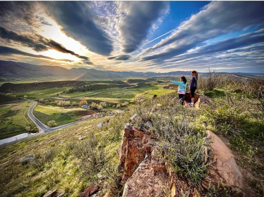 two people on an overlook looking at foothills and prarie