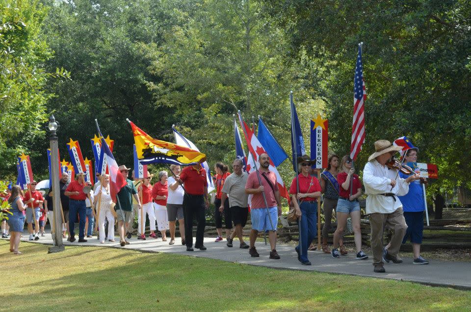 Acadian Culture Day Parade of people holding flags.