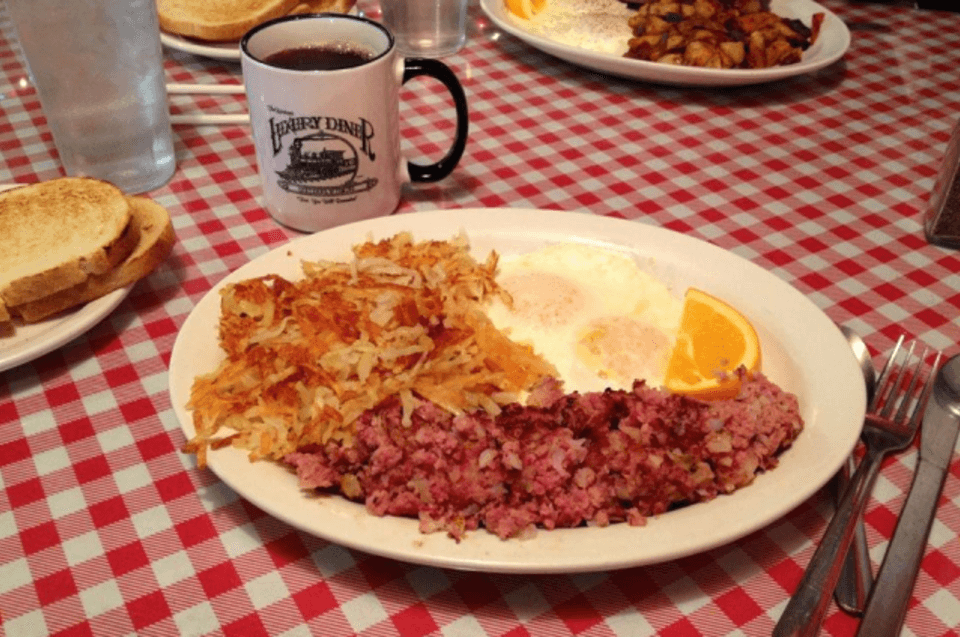 A local breakfast of corned beef hash and eggs sitting atop a red checkered tablecloth at Luxury Diner, Cheyenne.