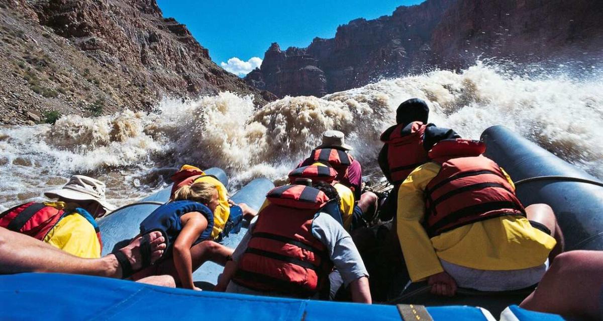 Rafters heading straight into large rapids while river rafting