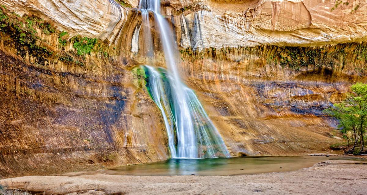 Lower Calf Creek Falls drop into a pool with a mossy cliff wall.