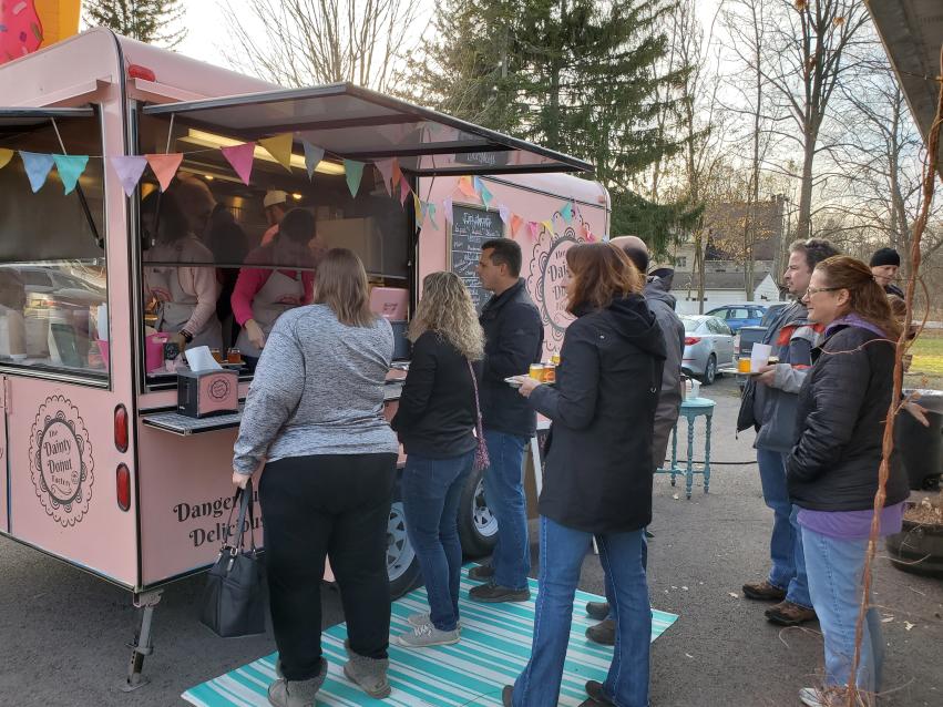 A group of people ordering and waiting outside the pink Dainty Donut food truck