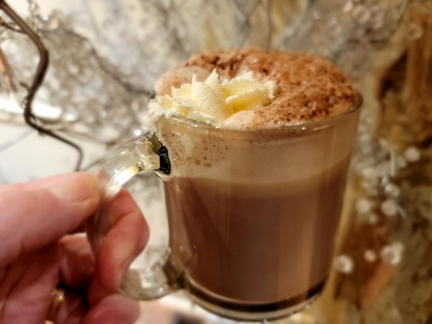 Hot chocolate in a clear cup. Held by a woman's hand
