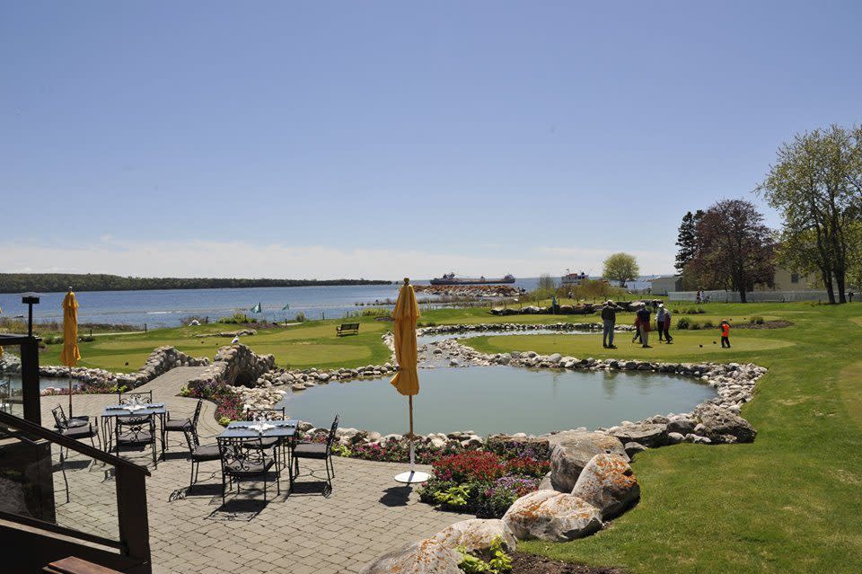 Outdoor tables at Bistro on the Greens at Mission Point Resort offer views of a golf putting course and the water