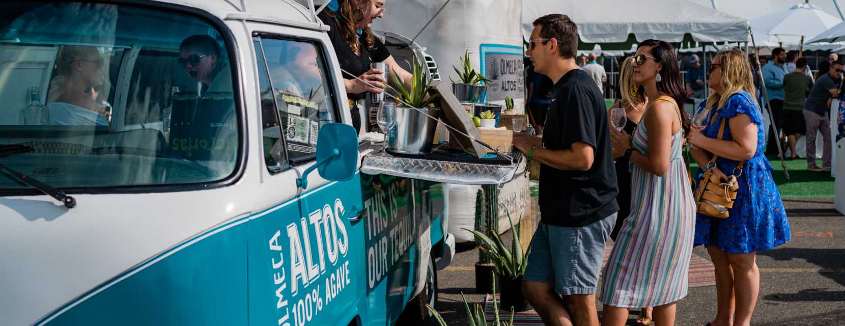 A server offers alcoholic drinks from a van to guests at the Denver Food + Wine Festival.
