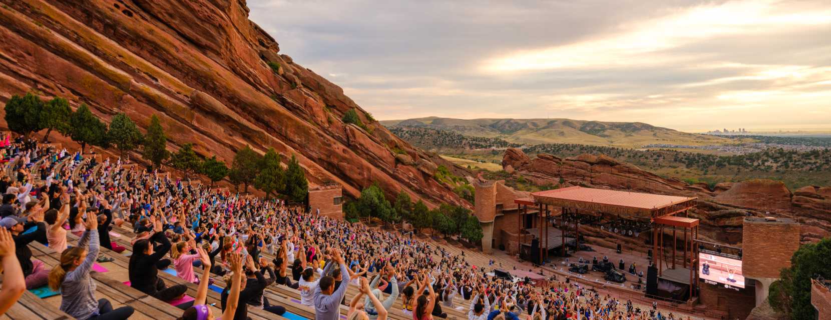 Hundreds of people practicing yoga in the stands at Red Rocks Park & Amphitheatre in Denver, Colorado.