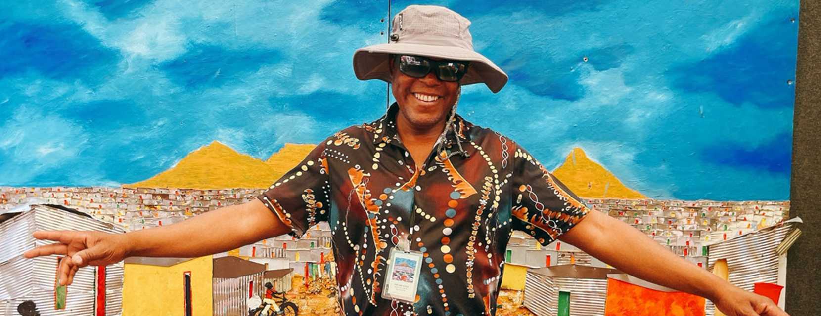 An artist stands in front of a painting at the Cherry Creek Arts Festival in Denver, Colorado.