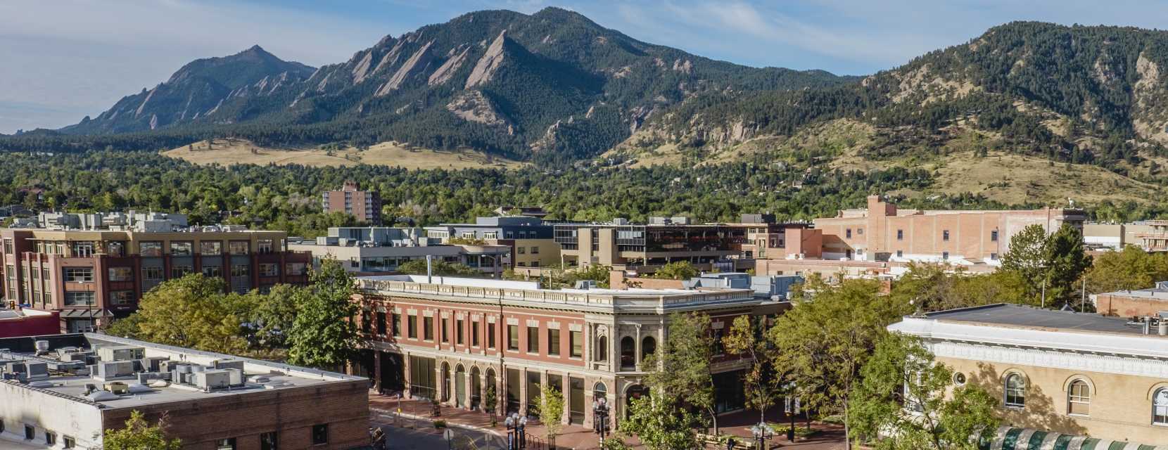 An aerial view of Boulder, Colorado's Pearl Street, with the Flatiron Mountains rising in the background