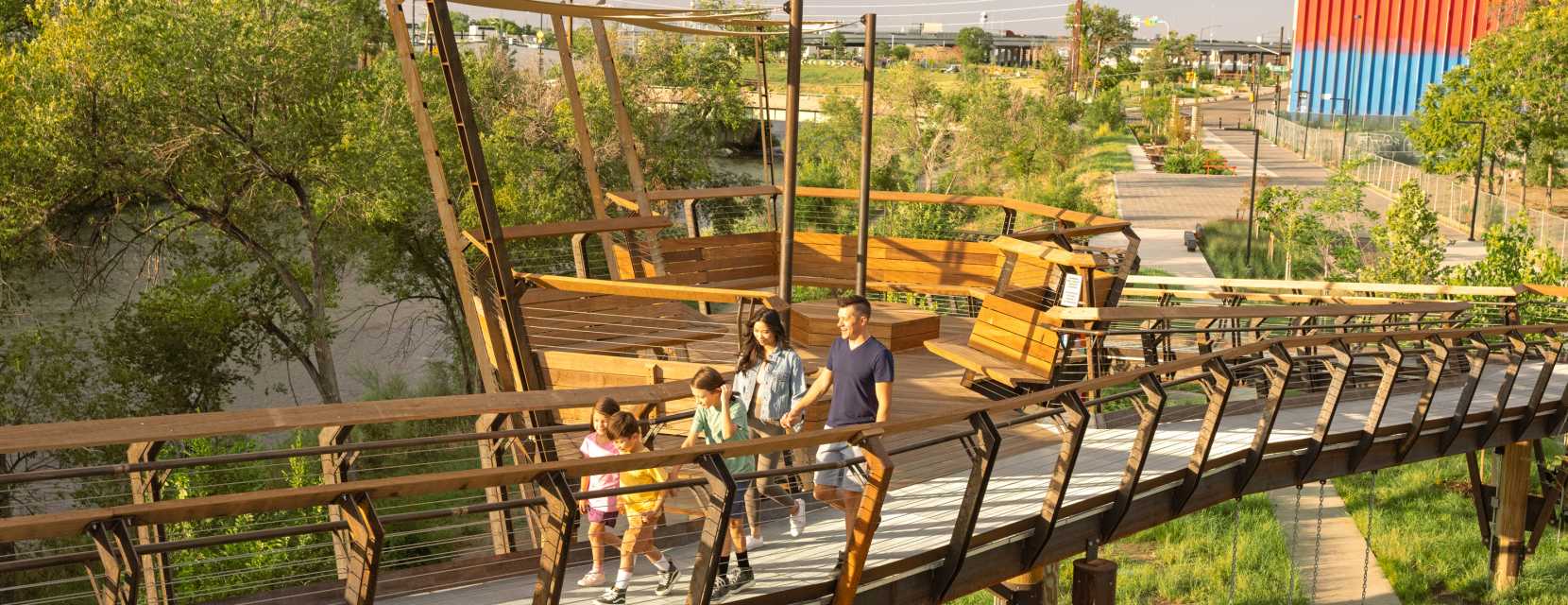 A family crosses the Arkins Promenade, an elevated walkway along the South Platte River in Denver, Colorado.
