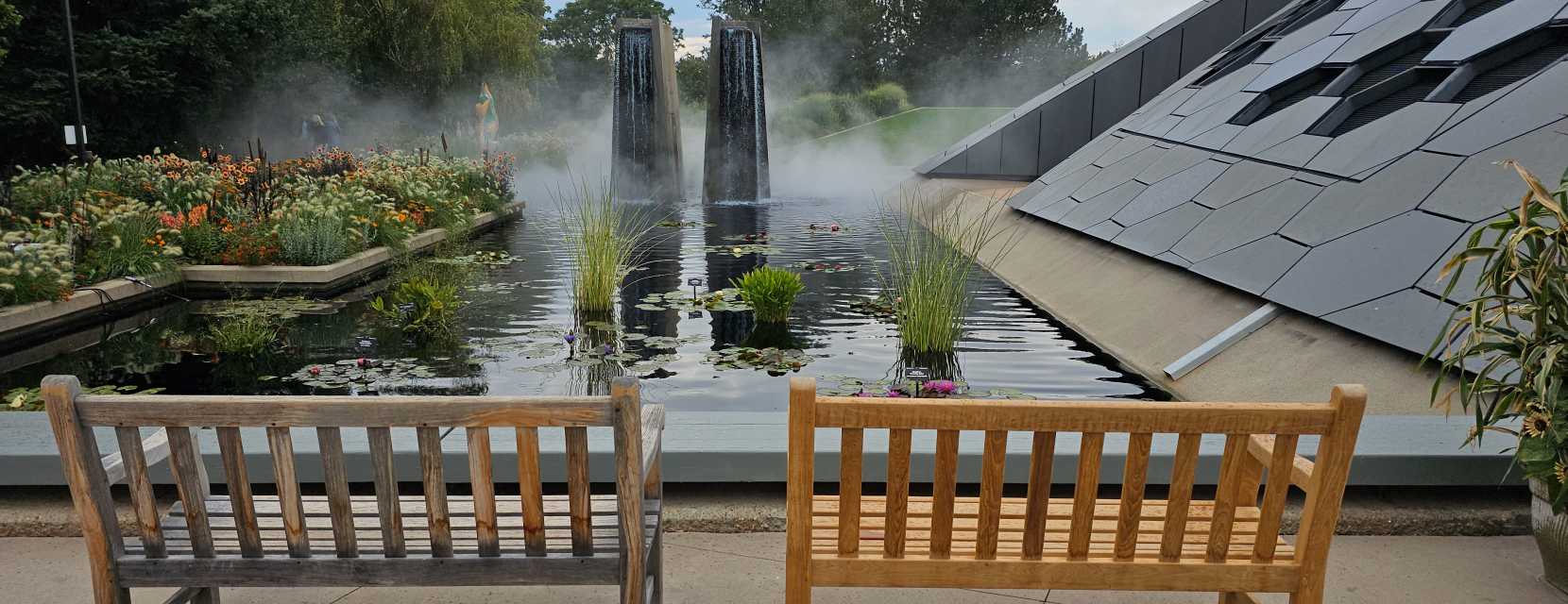Two wooden benches overlooking a pond at Denver Botanic Gardens