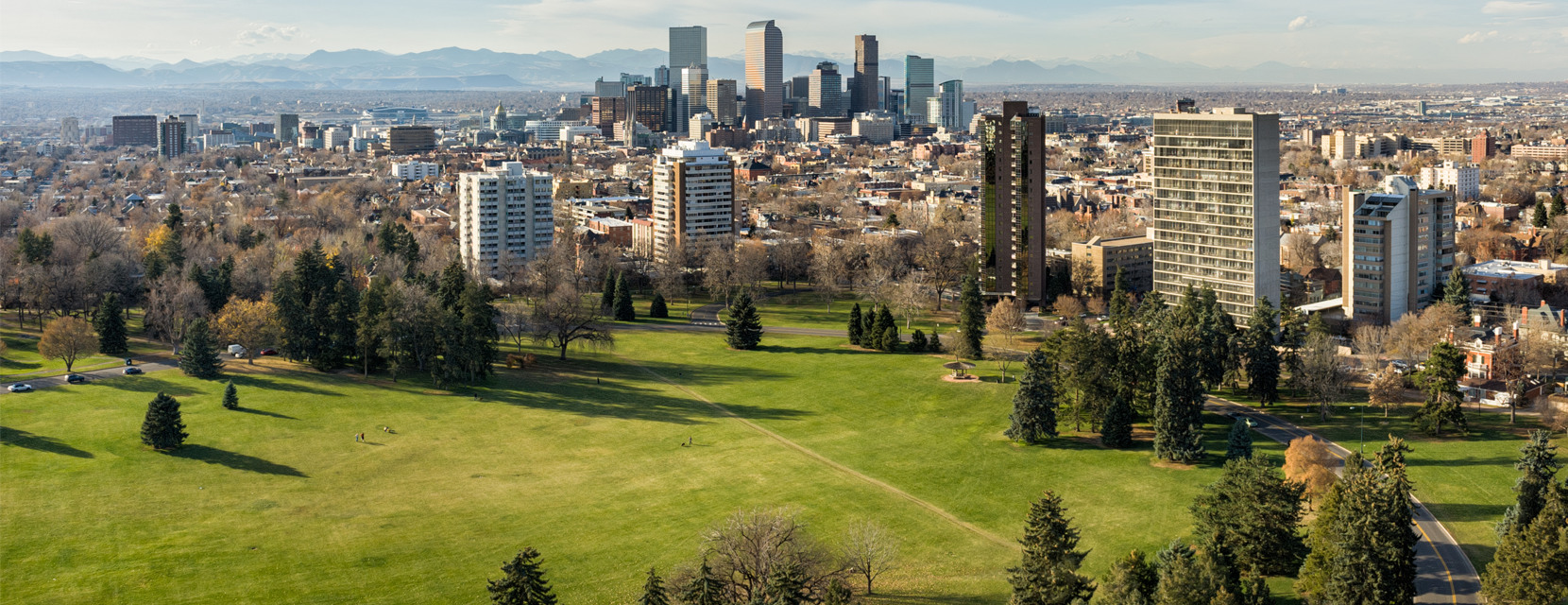 An aerial view of Cheesman Park's lawn with the skyline and mountains in the background.