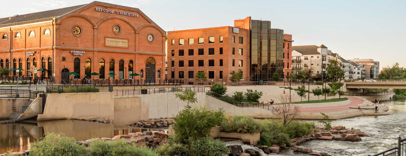 A wide view of Confluence Park in Denver, Colorado, with the REI building in the background.
