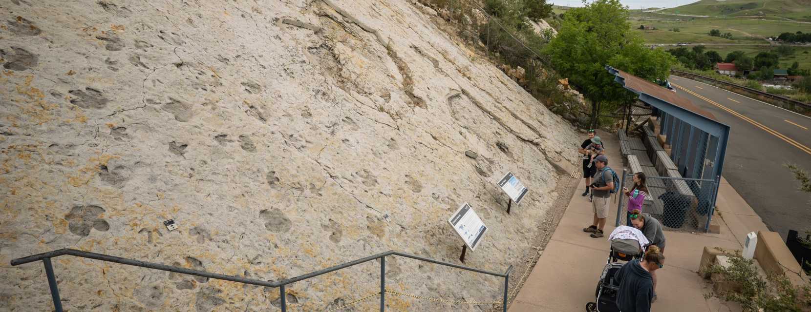 Several visitors and a dog are climbing the steps at Dinosaur Ridge in Denver, Colorado.