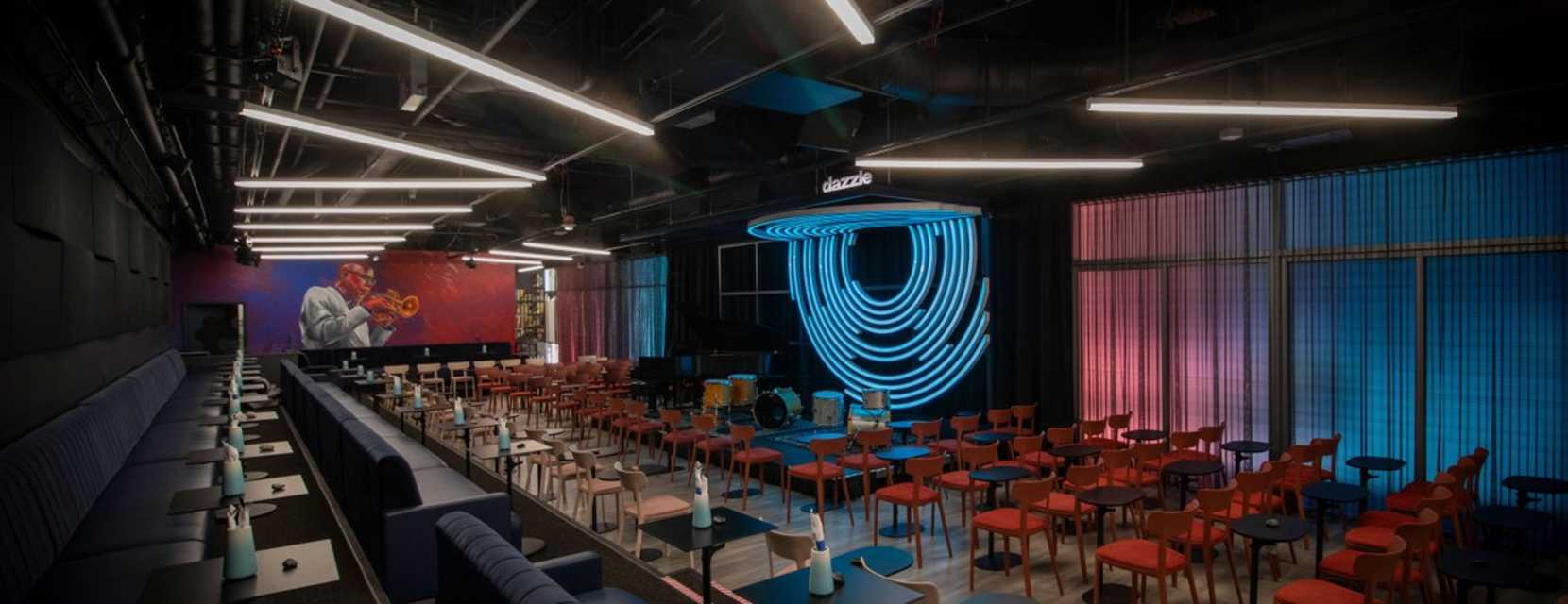 Interior of Dazzle Jazz Club with lush seating and cozy tables set in front of the stage