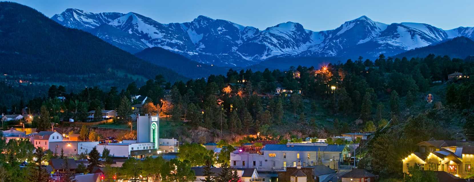 A wide landscape view of Estes Park, Colorado, with snow-capped mountains in the background.