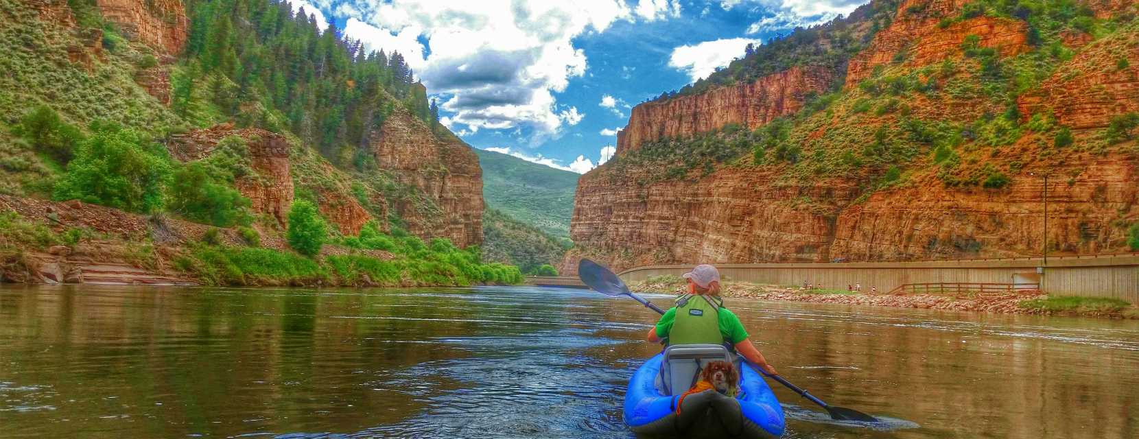 A person paddles along a peaceful river in Glenwood Springs, Colorado with red cliffs flanking the view