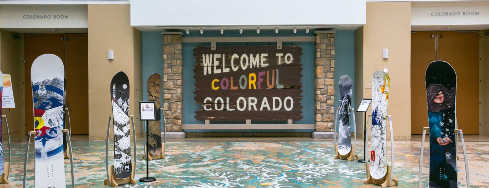 An exhibit hall featuring snowboards and a Colorado welcome sign at History Colorado Center in Denver.