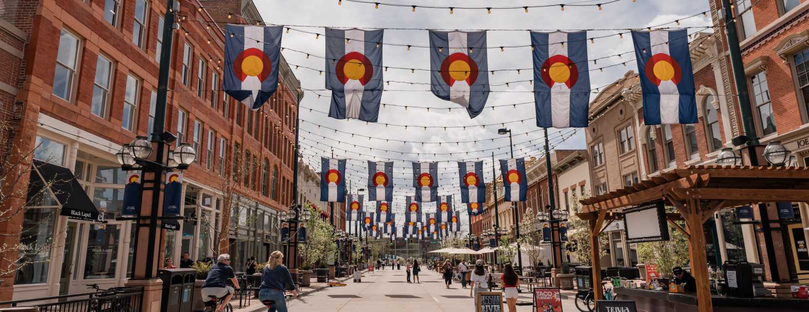 A wide view of Larimer Square in Denver, Colorado, where people are walking and riding bikes.