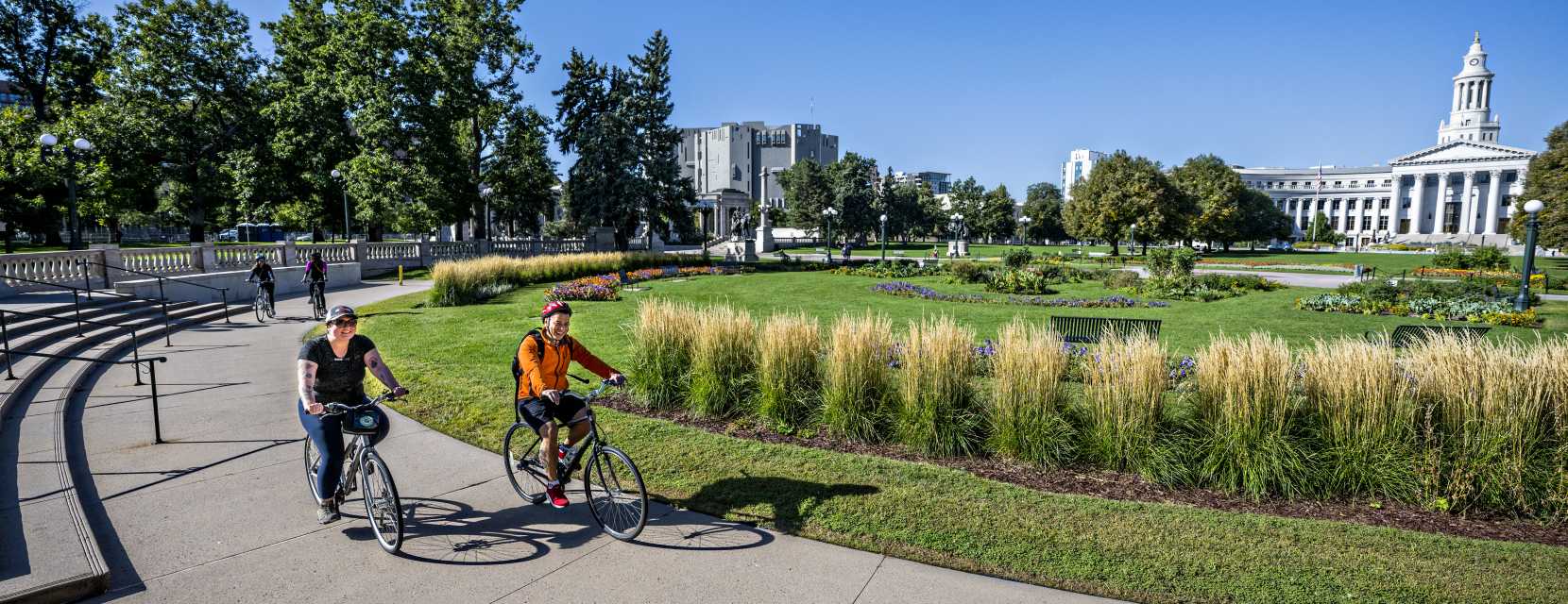 Two people riding bikes around a garden at Civic Center Park in Denver, Colorado.