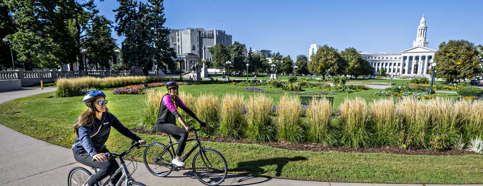Two people riding bikes around the gardens in Denver's Civic Center Park.