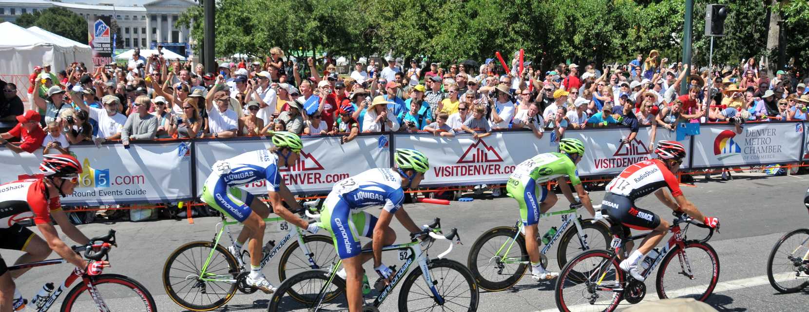 Bicyclists race on a road in Denver with the capitol in the background