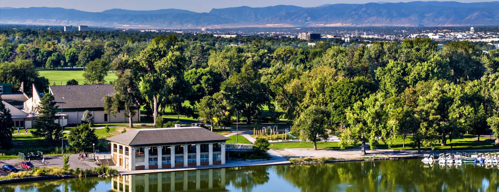 Aerial view of Washington Park in Denver, Colorado, showing a lake and mountains in the background.