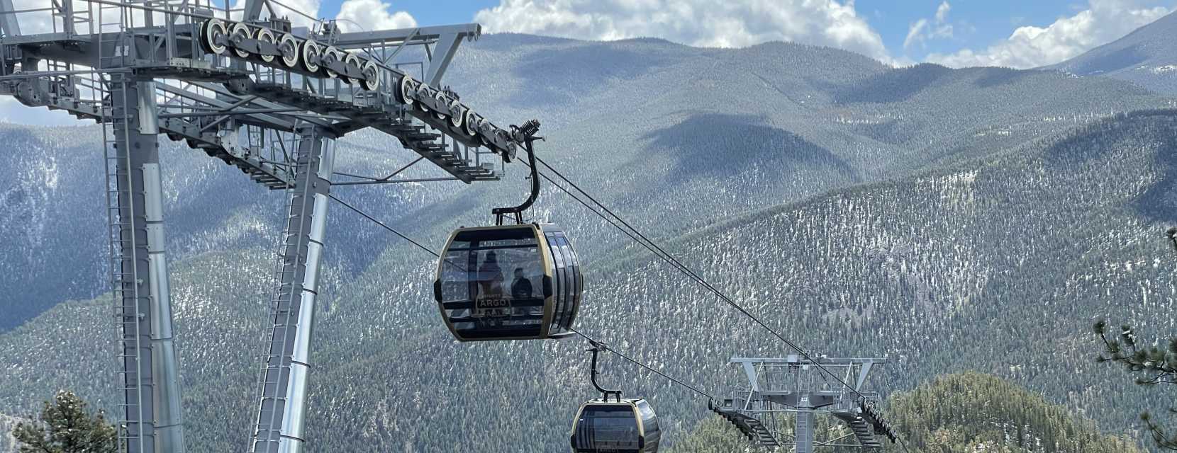 Two gondolas, as part of the Mighty Argo Cable Car attraction, rise above Idaho Springs, Colorado.