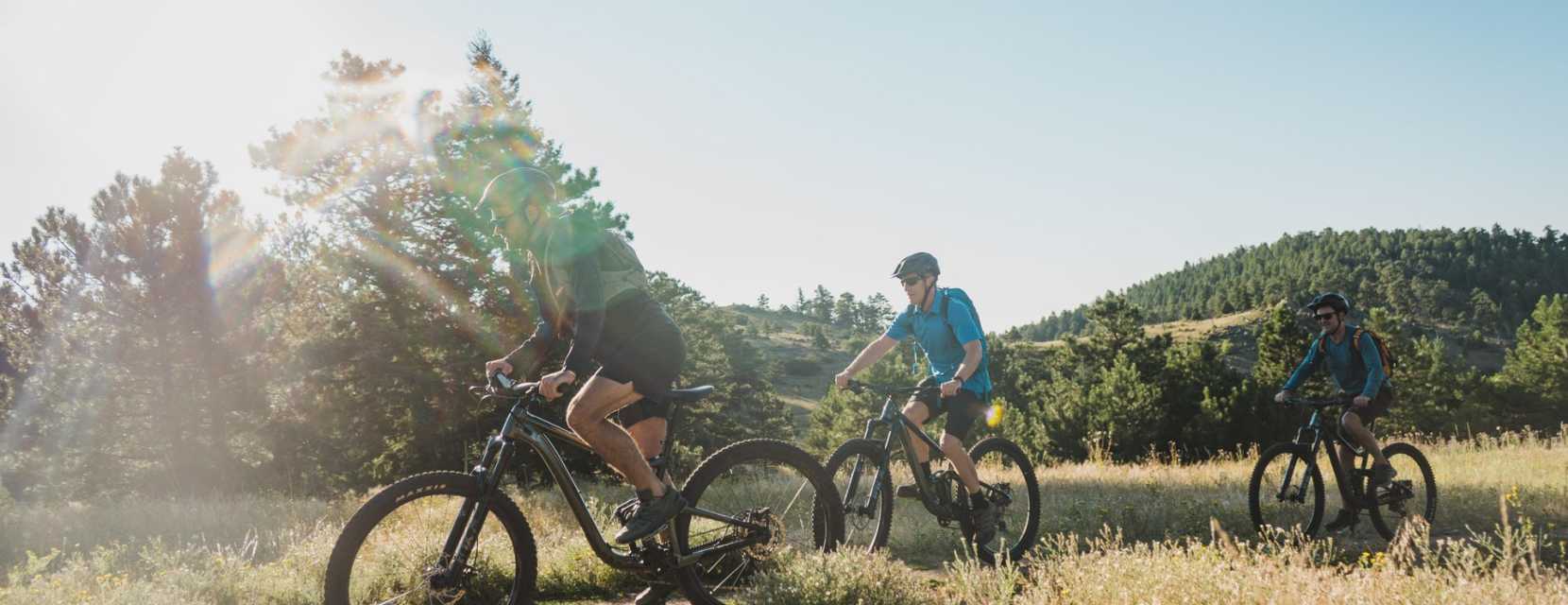 Three people bike along a trail near Denver