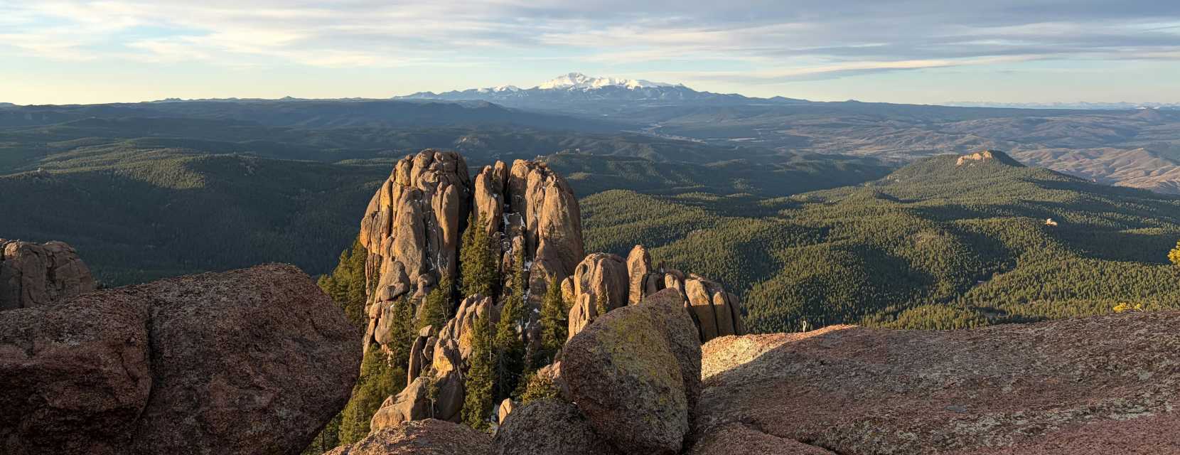 A view of a snowcapped mountain range in autumn with spires in the foreground at Devil's Head Lookout