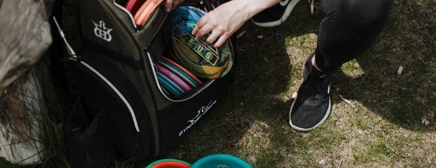 A person is taking discs out of a bag at a course