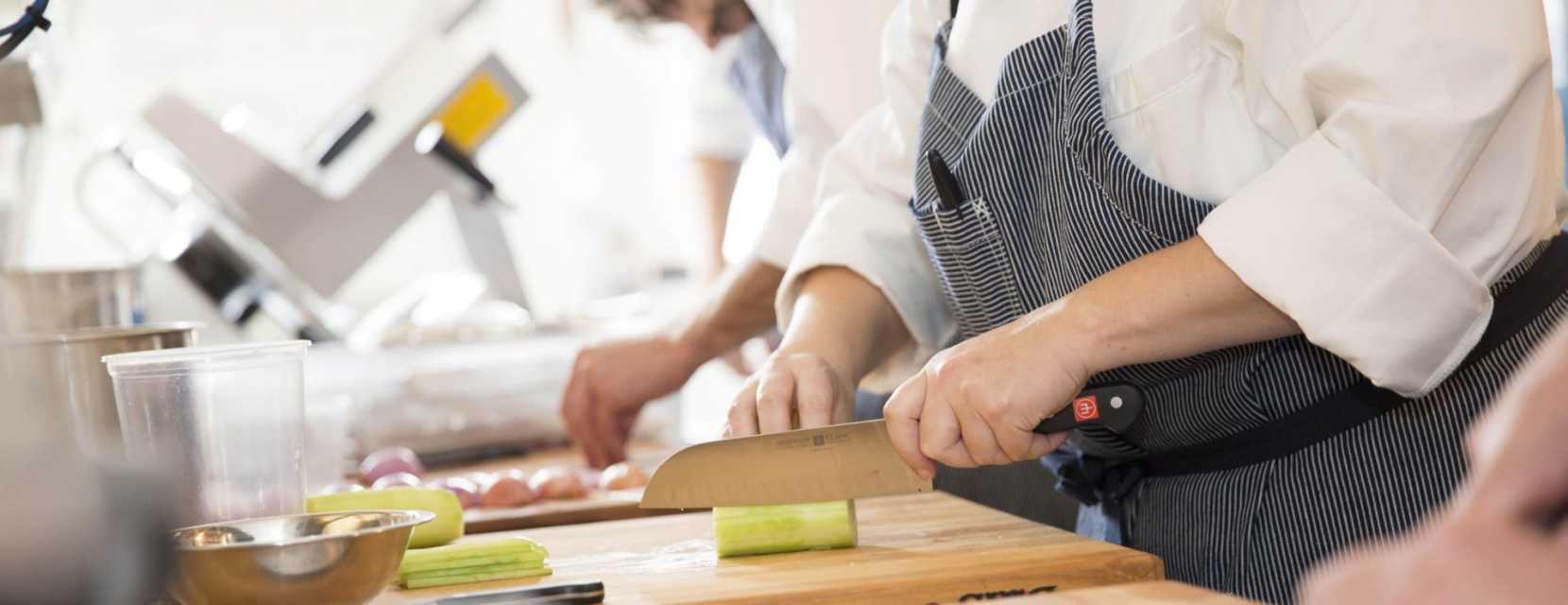 A chef chops a green vegetable on a wood cutting board at a farm-to-table restaurant in Denver, Mercantile Dining and Provision