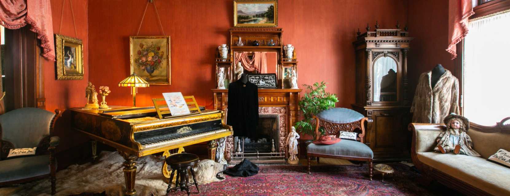 A piano, love seat and fireplace is visible in the living room at the Molly Brown House Museum