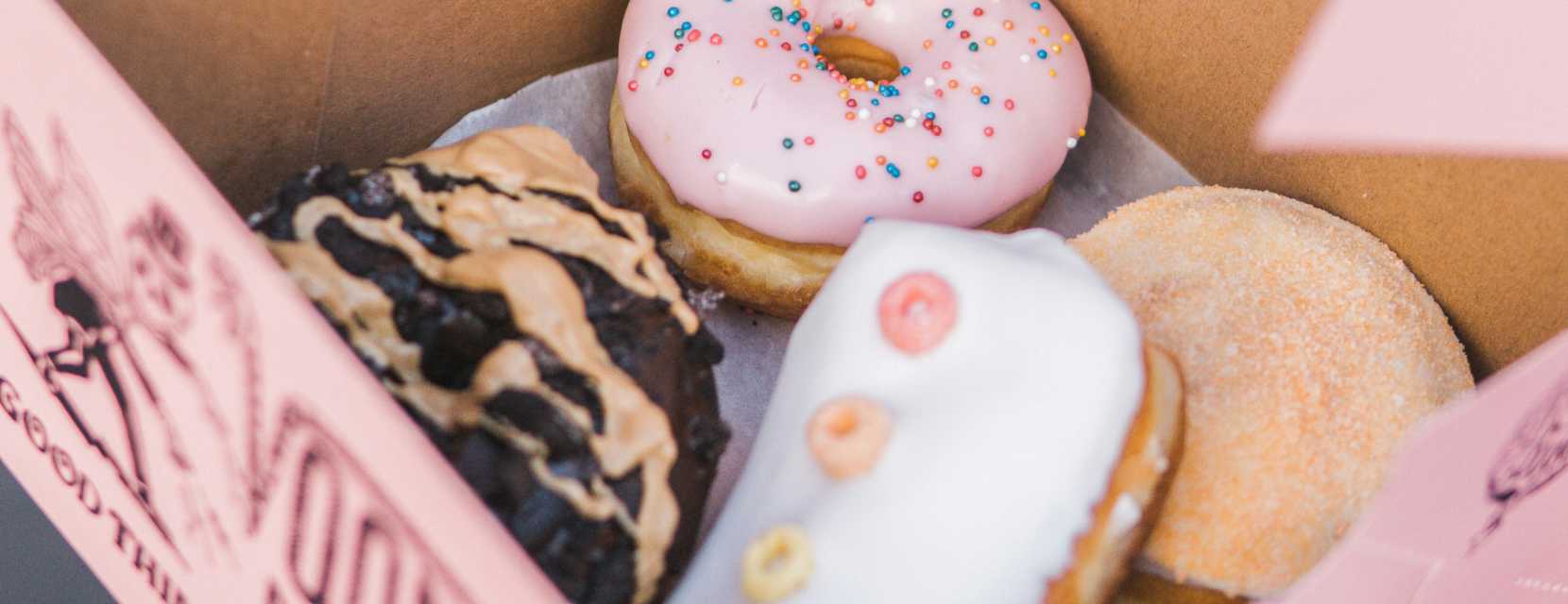A box of colorful doughnuts in a pink box from Voodoo Doughnut