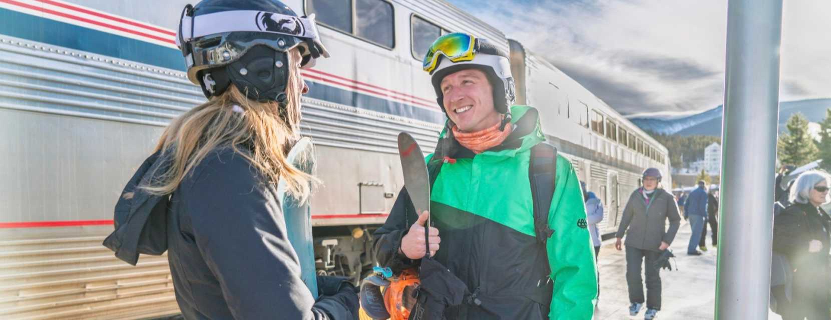 Two people in jackets talk as they wait to board the Winter Park Express Ski Train